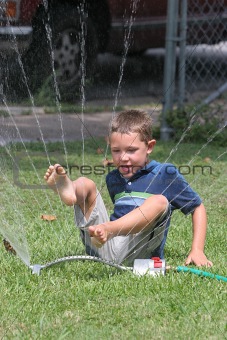 cute boy playing in sprinkler