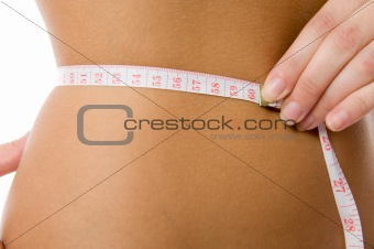 Close-up sexy woman measuring her waist with a measuring tape.