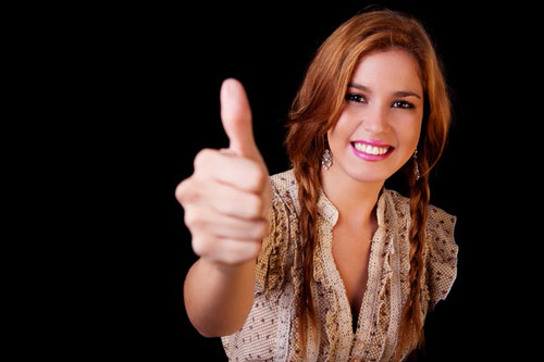 Young pretty women with thumb raised as a sign of success